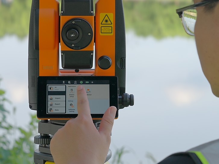 Dois topógrafos a efectuarem uma travessia de estação total ao longo de uma estrada, com o operador do instrumento a avistar um alvo de poste de prisma